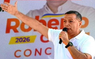 Roberto Cubilla Sanabria hablando al micrófono, con camiseta blanca y gesto enfático en evento político al aire libre.