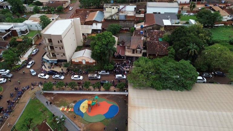 Grupo de personas reunidas frente a un edificio, la mayoría escuchando a un orador en un entorno urbano.