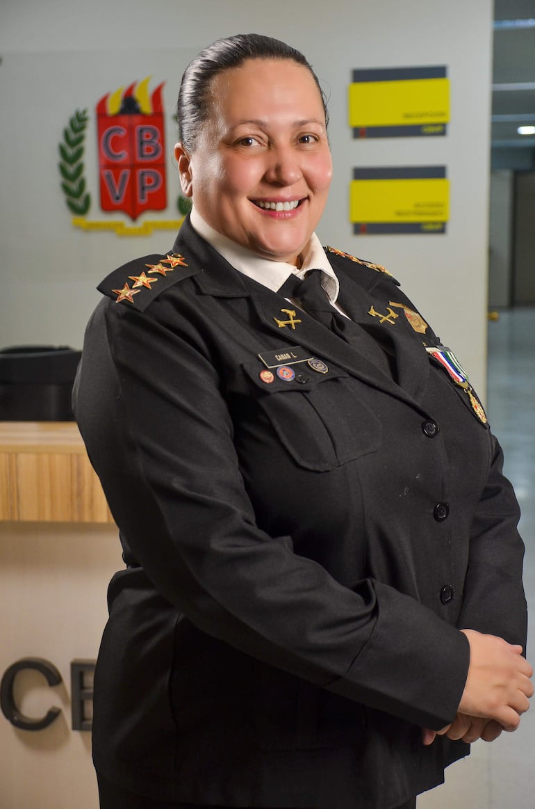 Lorena Canan en uniforme negro con condecoraciones sonríe, en un ambiente institucional decorado con el logo CBVP.