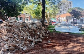 Espacio en construcción con escombros y árboles al fondo, sin personas visibles en la imagen.