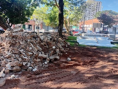 Espacio en construcción con escombros y árboles al fondo, sin personas visibles en la imagen.