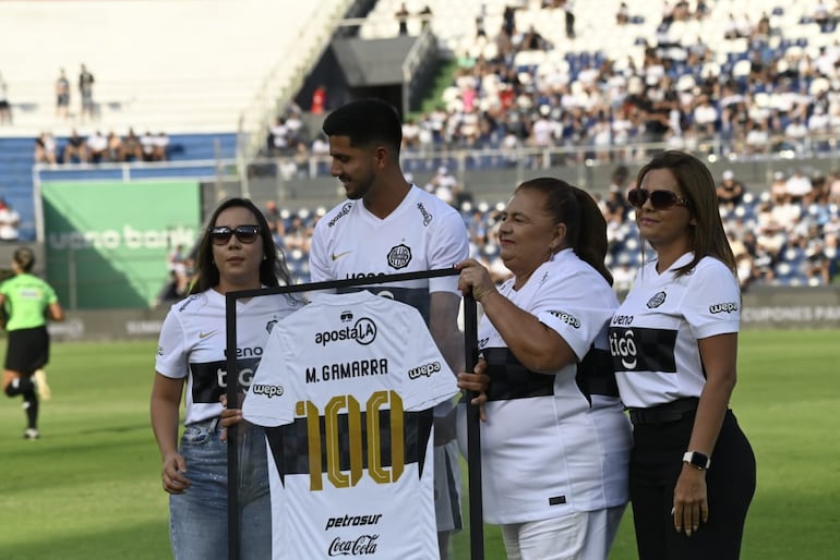 El zaguero de Olimpia, Mateo Gamarra recibe la camiseta enmarcada por el centenar de partidos acompañado por sus familiares.