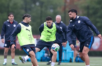 El delantero Julio Enciso intenta meter el pase ante la marca del zaguero Omar Alderete, mientras el mediapunta Enso González acompaña la acción.