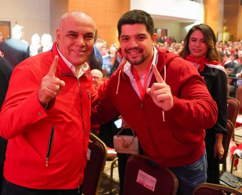 Basilio Núñez y José Rodríguez Robertti sonríen y levantan el dedo, señal de la Lista 1, en un auditorio abarrotado.