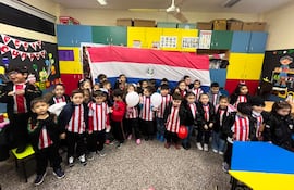 Niños del CEPB con camisetas de Olimpia, algunos sosteniendo globos, celebran antes de un partido con alegría en un aula decorada.