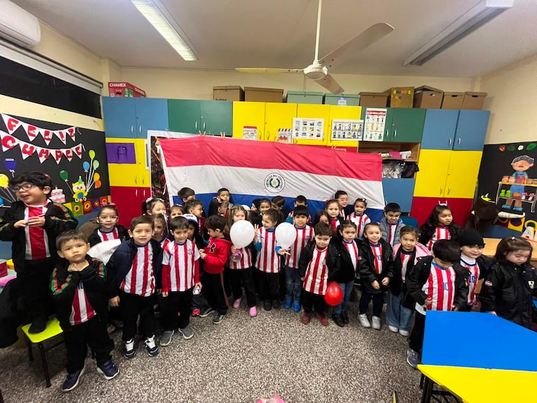 Niños del CEPB con camisetas de Olimpia, algunos sosteniendo globos, celebran antes de un partido con alegría en un aula decorada.