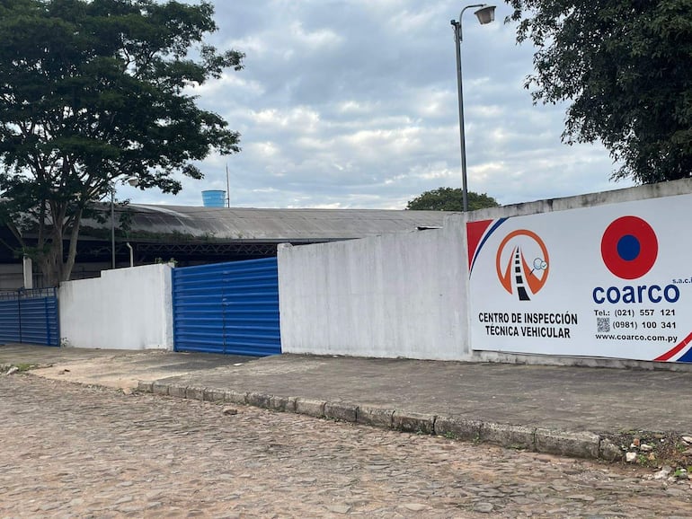 Exterior del Centro de Inspección Técnica Vehicular Coarco, con cartel visible y cercas blancas y azules en un día nublado.