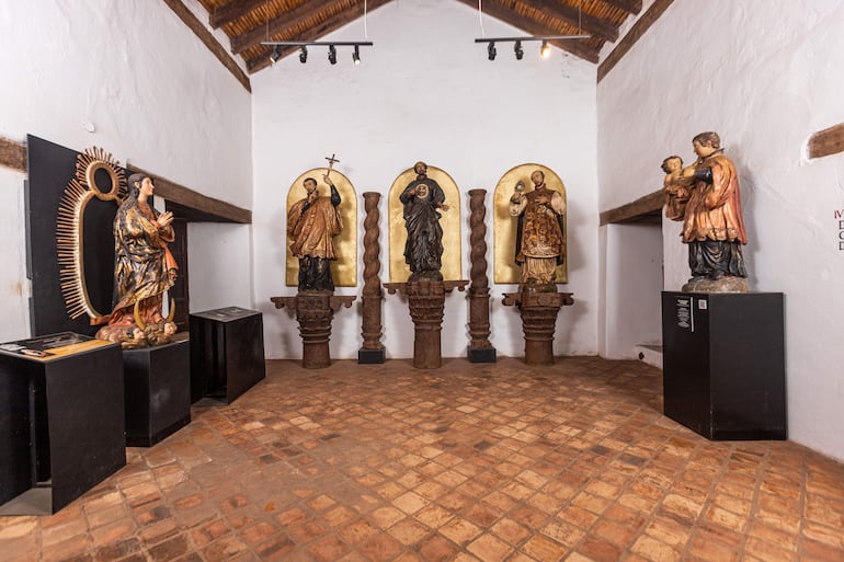 Estatuas de figuras religiosas, destacando una Virgen María y santos en un entorno iluminado con focos.