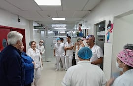 Once enfermeros, en su mayoría con uniformes blancos, sonríen y conversan en un pasillo iluminado del hospital.