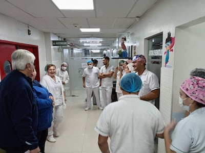 Once enfermeros, en su mayoría con uniformes blancos, sonríen y conversan en un pasillo iluminado del hospital.