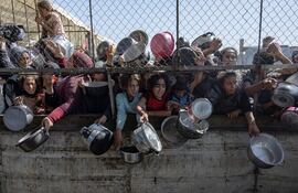 Palestinos desplazados se agolpan frente a un comedor social para recibir raciones limitadas ante la escasez de alimentos, en Khan Younis, sur de la Franja de Gaza, este viernes. Naciones Unidas advirtió que "toda la población de Gaza corre el riesgo de hambruna" desde que Israel cerró los cruces fronterizos el 2 de marzo de 2025, impidiendo la entrada de suministros esenciales. La Oficina de Medios del Gobierno de Gaza informó el 24 de mayo que al menos 58 personas murieron por desnutrición y casi 250 más por falta de alimentos y medicamentos. EFE/ Haitham Imad