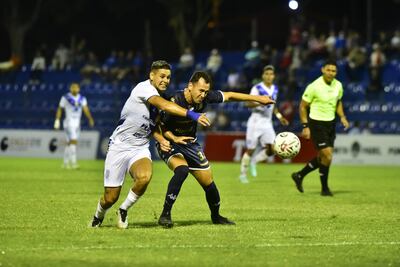 Sergio Bareiro, futbolista de Sportivo Ameliano, y Francisco Báez (d), jugador de Nacional, pelean por el balón en un partido del fútbol paraguayo en el estadio Luis Alfonso Giagni, en Villa Elisa.