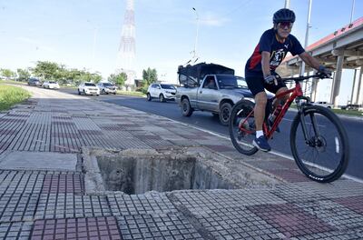 Actual estado de la Costanera Norte es un peligro de muerte para sus usuarios. El la foto, un ciclista pasa por el angosoto espacio que deja un enorme pozo en el que un niño cayó el fin de semana.