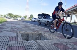Actual estado de la Costanera Norte es un peligro de muerte para sus usuarios. El la foto, un ciclista pasa por el angosoto espacio que deja un enorme pozo en el que un niño cayó el fin de semana.