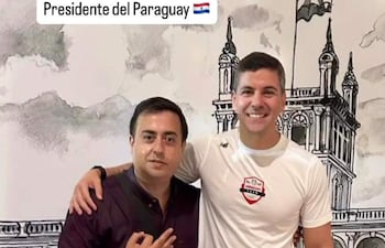 Santiago Peña en camiseta blanca y pantalones cortos, sonriente, junto a otro hombre con mochila en un entorno deportivo.
