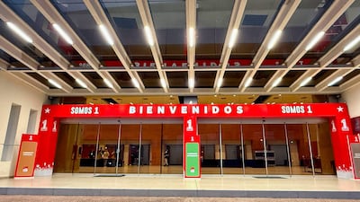 Entrada del edificio de Conmebol decorada con letreros que dicen 'BIENVENIDOS' y 'SOMOS 1' en un ambiente moderno.