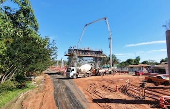 Obra en construcción mostrada con camiones mixer y brazos mecánicos, sin personas visibles en un día despejado.