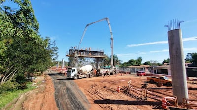 Obra en construcción mostrada con camiones mixer y brazos mecánicos, sin personas visibles en un día despejado.