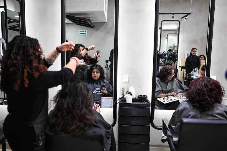 La estilista Ariana Leon (I), de 29 años, corta el cabello de una clienta en un salón de belleza que apoya una iniciativa de representantes de la Fundación Matter of Trust Latam, quienes procesan el cabello recolectado para utilizarlo en el ahorro de agua y como fertilizante para plantas en una chinampa (jardín flotante), en Ciudad de México el 11 de febrero de 2026.