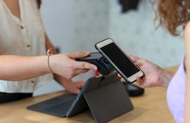 Una mujer realiza un pago electrónico utilizando su teléfono celular en un pos.