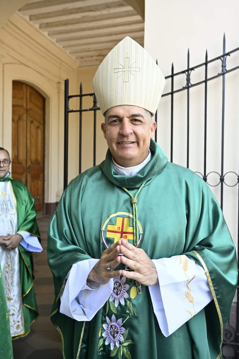 Gabriel Escobar sonríe en túnica verde mientras sostiene un báculo, acompañado de otro religioso en vestimenta blanca y verde.
