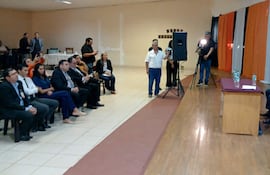 Rafael Filizzola, de cabello canoso y traje claro, habla mientras Esperanza Martínez lo observa, decoraciones en colores de la bandera paraguaya.