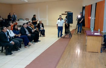 Rafael Filizzola, de cabello canoso y traje claro, habla mientras Esperanza Martínez lo observa, decoraciones en colores de la bandera paraguaya.
