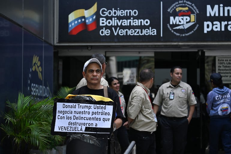 Un familiar de un preso político sostiene una pancarta que dice "Donald Trump: Negocias nuestro petróleo con los criminales que destruyeron Venezuela", durante la marcha "¿Cuánto petróleo cuestan nuestros presos?" frente al Ministerio de Servicios Penitenciarios en Caracas, el 1 de septiembre de 2026. Familiares de presos políticos se manifiestan en Caracas