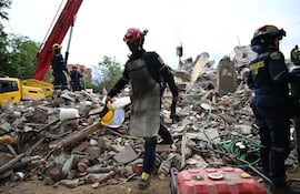 Colombian firefighters remove debris at the Torres del Limonar residential complex, located in the Capri neighborhood in southern Cali, Colombia, on August 16, 2026, after a 7.4- magnitude earthquake. At least 287 people have died, thousands have been injured and about 379 remain unaccounted for, as the chances of finding earthquake survivors have dropped sharply since the critical 72-hour window passed, though volunteers and rescue crews continue digging through the rubble for any signs of life. (Photo by Raul ARBOLEDA / AFP)