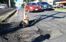 Bache en la calle Guatemala y Félix Bogado con cono de señalización, pavimento deteriorado y charcos de agua.