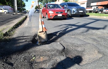 Bache en la calle Guatemala y Félix Bogado con cono de señalización, pavimento deteriorado y charcos de agua.