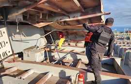 Un trabajador verifica la estructura de la barcaza siniestrada, luego de la explosión registrada este sábado y que dejó cinco fallecidos.