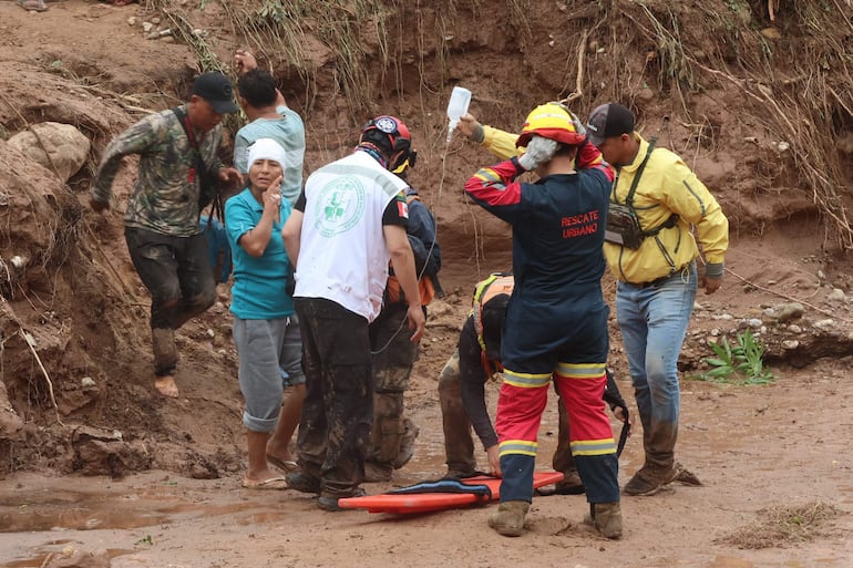 Personal de salud y equipos de rescate asisten a una persona afectada tras el desbordamiento de un río este sábado, en El Torno (Bolivia).