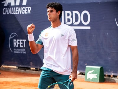 Daniel Vallejo, en camiseta blanca y pantalones cortos verdes, levanta la mano en celebración en la cancha de tenis.