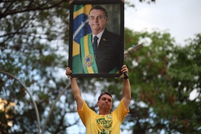 El candidato a presidente de Brasil, Flavio Bolsonaro, sostiene un retrato de su padre, Jair Bolsonaro.