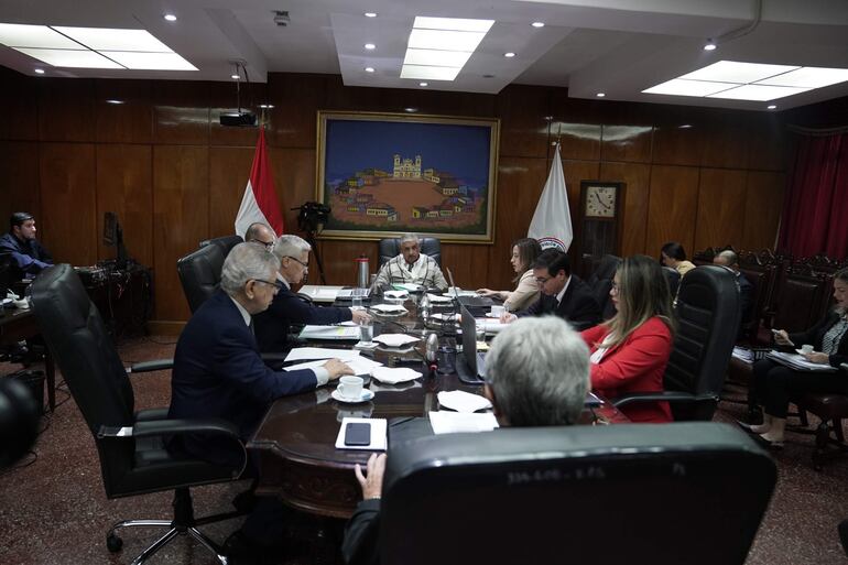 Isaías Ricardo Fretes, con vestimenta clara, habla mientras José Jara Rojas lo escucha, rodeados de documentos y decoración de madera.