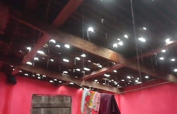 Techo dañado en vivienda, goteras visibles, paredes rojas y trapos colgados, indicando daño por granizada.