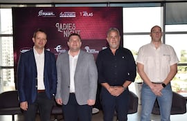 Cuatro hombres en trajes posan frente a un cartel de 'LADIES NIGHT', en un entorno luminoso con logotipos de sponsors.