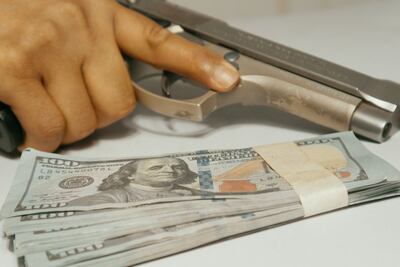 Imagen ilustrativa de sicariato, robo, delincuencia, arma y dólares.