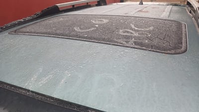 Techo de un vehículo cubierto de gotas de lluvia, en un entorno exterior con fondo rojizo.