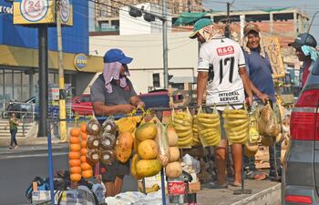 Vendedores ambulantes se protegen del intenso sol con quepis, mangas largas y toallas.