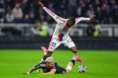 Julio Enciso case al piso ante la marca de Clinton Mata, defensor angoleño del Lyon. (AFP).