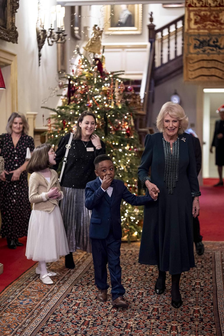 La reina Camila de Gran Bretaña toma de la mano a Samuel mientras se unen a ella los niños en la tradición anual de decorar el árbol de Navidad de Clarence House en Londres. (Aaron Chown / POOL / AFP)