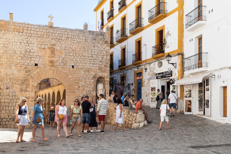 Tturistas caminan por la puerta de la fortaleza medieval Dalt Vila hasta las estrechas y pintorescas calles de este antiguo distrito de Eivissa en Ibiza, España.