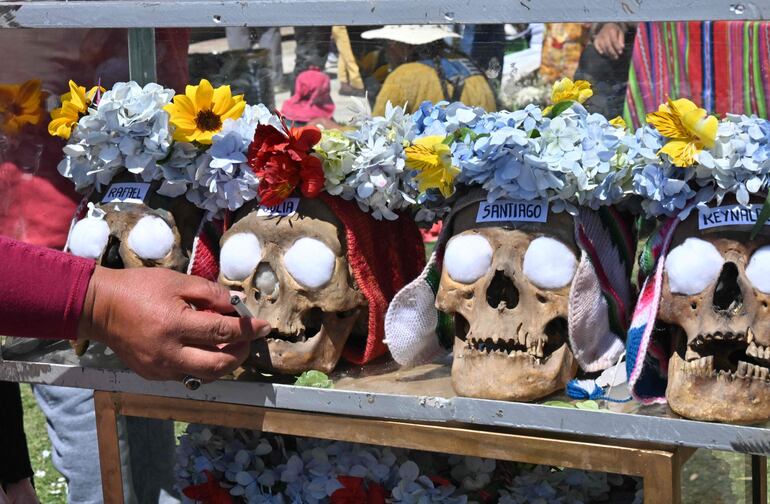 TOPSHOT - A woman places a cigarette on a natita (human skull) at the general cemetery in La Paz on November 8, 2024, as Bolivia celebrates the annual Natitas Festival. Known locally as Natitas, the festival, which is believed to be pre-Colombian, sees families adorn skulls, sometimes those of relatives, with flowers, hats, candles and other decoration. (Photo by AIZAR RALDES / AFP)
