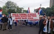 Médicos con batas blancas sosteniendo un cartel que dice 'HUELGA NACIONAL DE MEDICOS' en una calle rodeada de árboles.