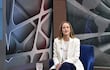 Soledad Núñez sentada en sillón azul, luce chaqueta blanca y camiseta con texto 'ACTIÓN' en un ambiente de estudio moderno.