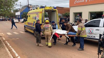 Bomberos y rescatistas en la calle, trasladando a un hombre cubierto con una manta en camilla.