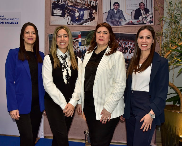 Cuatro mujeres vestidas profesionalmente sonríen en un entorno decorado durante el aniversario de LA Consolidada.
