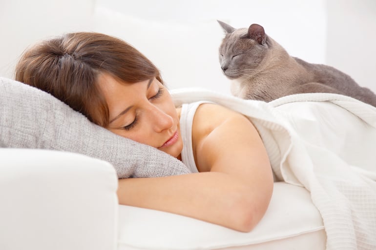 Mujer duerme con un gato.